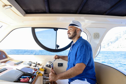 Man wearing hat driving motorboat - EIF02110