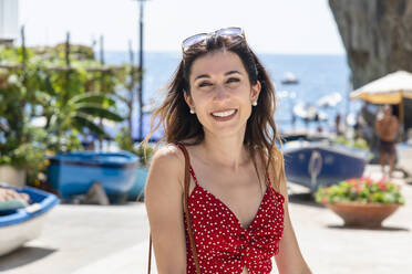 Smiling woman in red summer dress at beach - EIF02136