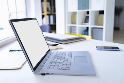 Laptop und Mobiltelefon auf dem Schreibtisch im Büro - GIOF13733