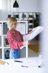 Businesswoman reading business plan in office - GIOF13750