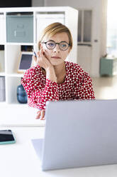 Nachdenkliche Frau mit Blick auf den Laptop im Büro - GIOF13756