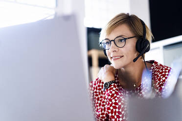 Female customer service representative working on laptop in office - GIOF13759