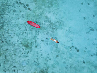 Frau mit Surfbrett schwimmt im Meer auf der Insel Huraa, Malediven - KNTF06426
