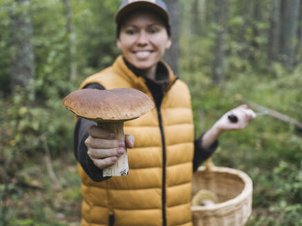 Lächelnde Frau mit Pilz im Wald - KNTF06442