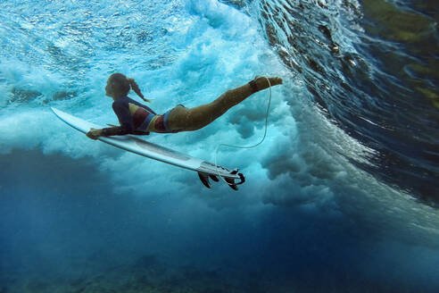 Mittlere erwachsene Frau mit Surfbrett schwimmt unter Wasser - KNTF06469