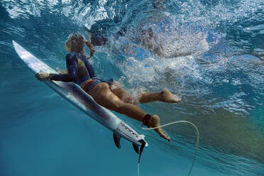 Frau mit Surfbrett taucht unter Wellen - KNTF06470