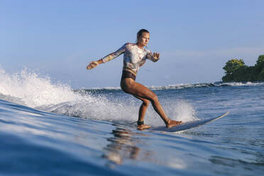 Frau im Badeanzug beim Surfen an Bord im Urlaub - KNTF06487