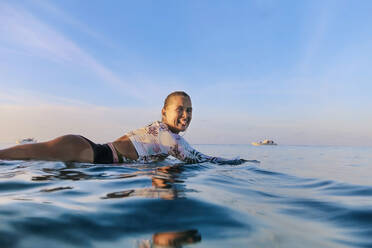 Happy woman sticking out tongue while floating on water - KNTF06490