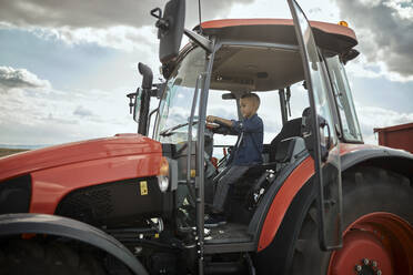 Boy driving tractor in field - ZEDF04270