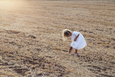 Kleines blondes Mädchen allein auf einem Feld an einem sonnigen Tag - ADSF30998