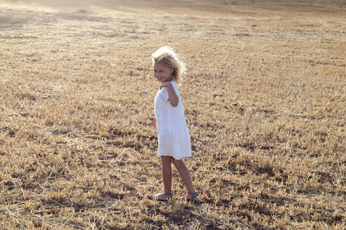 Kleines blondes Mädchen allein auf einem Feld an einem sonnigen Tag - ADSF30999