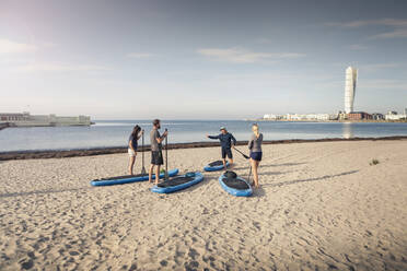 Männlicher Ausbilder trainiert Mann und Frauen am Strand im Urlaub - MASF25754
