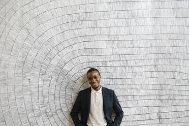 Smiling male professional standing in front of wall at convention center - MASF25923