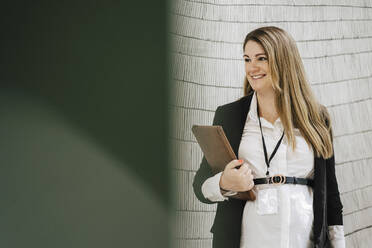 Smiling pregnant businesswoman standing with file while looking away - MASF26022
