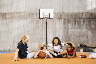 Porträt eines Mädchens, das mit seinen Freundinnen auf dem Basketballplatz sitzt - MASF26044