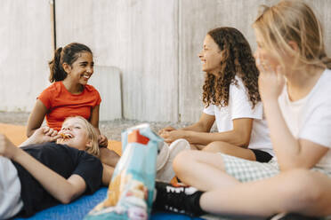 Happy multi-ethnic girls having snack at basketball court - MASF26050