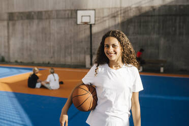 Lächelndes Mädchen mit Basketball auf dem Basketballplatz - MASF26053