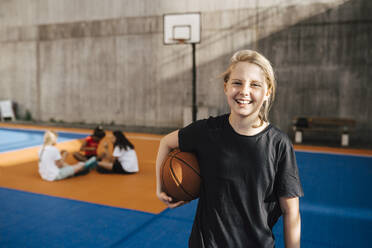 Portrait of smiling girl with basketball at sports court - MASF26054