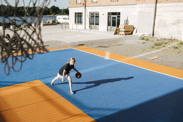 Hoher Winkel Ansicht des Mädchens dribbelnden Ball am Basketballplatz auf sonnigen Tag - MASF26060