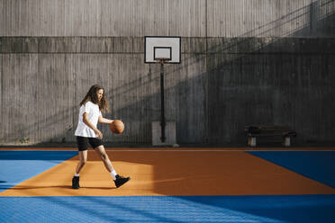 Eine Basketballspielerin dribbelt den Ball auf einem Sportplatz - MASF26062