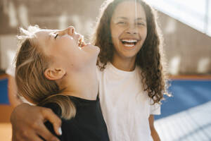 Fröhliche Freundinnen lachen am Basketballplatz an einem sonnigen Tag - MASF26080