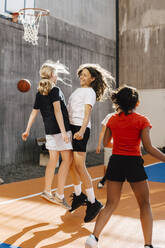 Female friends celebrating after goal at basketball court - MASF26096