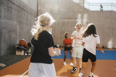 Cheerful female friends playing at basketball court - MASF26098