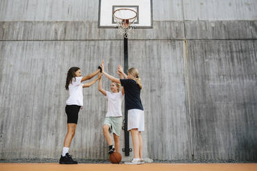 Female friends doing high-five while standing at basketball court - MASF26112