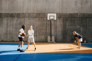 Pre-adolescent female basketball players playing at sports court - MASF26113