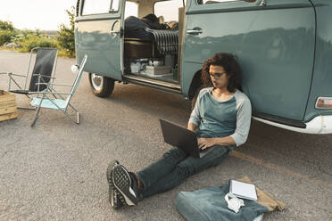 Mann mit Laptop, der an einem Campingwagen sitzt - MASF26214