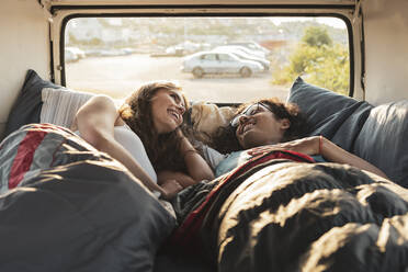 Young couple relaxing while lying in van - MASF26228