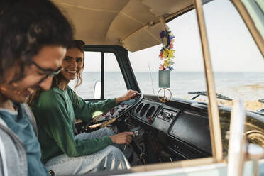 Lächelnde Frau im Gespräch mit einem männlichen Freund im Campingbus während einer Autoreise - MASF26229