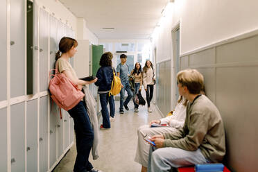Teenage girls and boys in illuminated school corridor - MASF26282