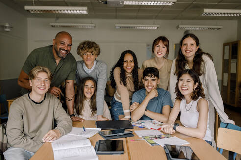 Porträt von lächelnden Teenager-Mädchen und Jungen mit männlichem Professor im Klassenzimmer - MASF26284