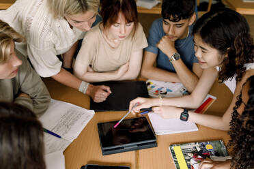 Multi racial girls and boys with female teacher studying over digital tablet in classroom - MASF26289