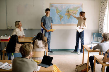 Teenager und Mädchen erklären über Weltkarte im Klassenzimmer - MASF26302