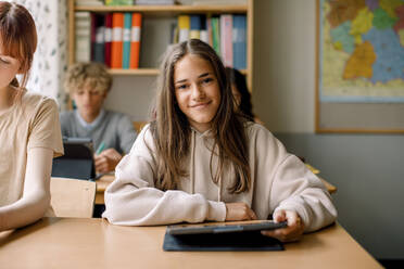 Lächelndes Mädchen hält digitales Tablet im Klassenzimmer - MASF26310