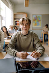 Blonder Teenager mit Buch und digitalem Tablet im Klassenzimmer einer High School - MASF26321