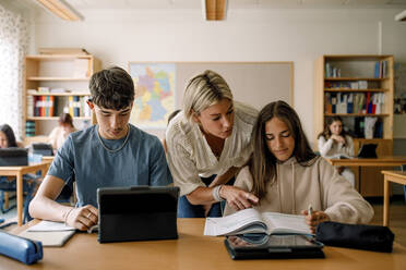 Female teacher teaching teenage girl on book in classroom - MASF26333