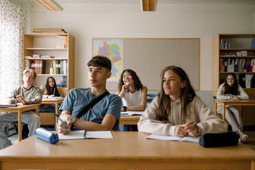 Lächelnde Studenten, die am Schreibtisch im Klassenzimmer lernen - MASF26338