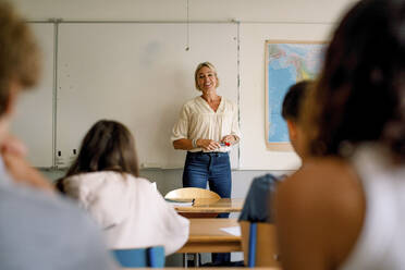 Lächelnde Professorin unterrichtet Studenten im Klassenzimmer einer High School - MASF26342