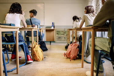 Eine gemischtrassige Gruppe von Schülern sitzt am Schreibtisch im Klassenzimmer - MASF26344