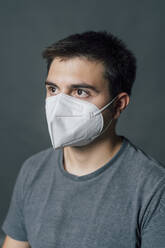 Junger Mann mit Schutzmaske während einer Pandemie - MEUF04277
