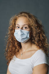 Junge Frau trägt Schutzmaske während der Pandemie - MEUF04294