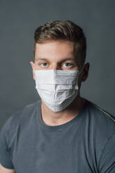 Young man wearing protective face mask in studio during pandemic - MEUF04299