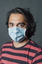 Man in striped t-shirt wearing protective face mask during COVID-19 - MEUF04307