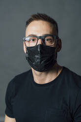 Mittlerer Erwachsener mit Brille und Gesichtsschutzmaske im Studio - MEUF04312