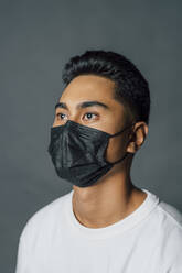 Young man in protective face mask during COVID-19 - MEUF04324