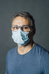 Mature man wearing protective face mask in studio during pandemic - MEUF04335