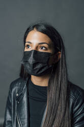 Junge Frau mit Gesichtsschutzmaske im Studio während einer Pandemie - MEUF04341